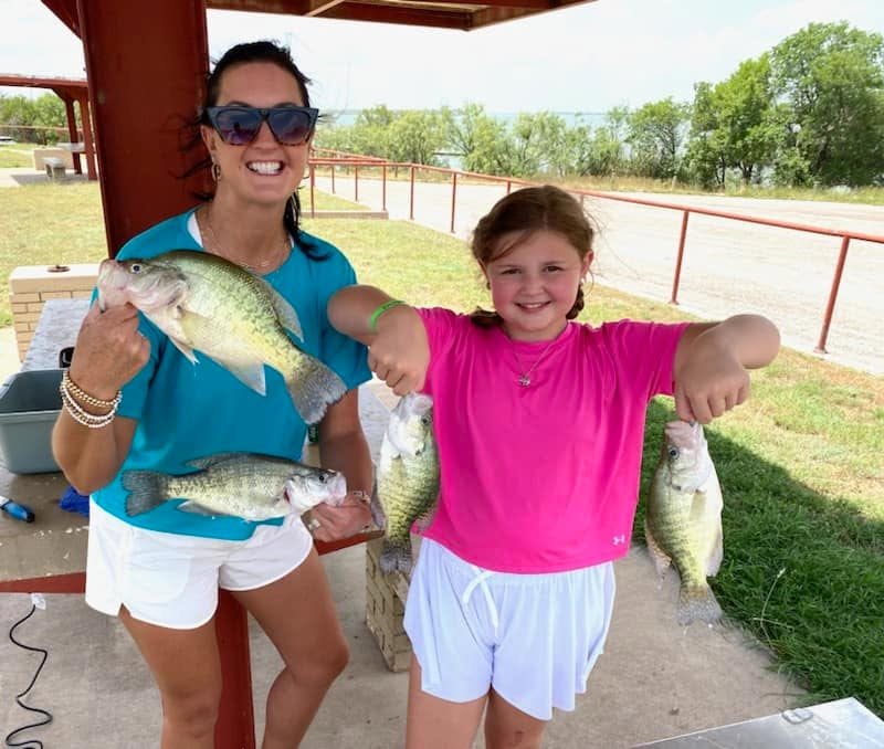 Two smiling guests holding four fish after a Krappie Katcher trip